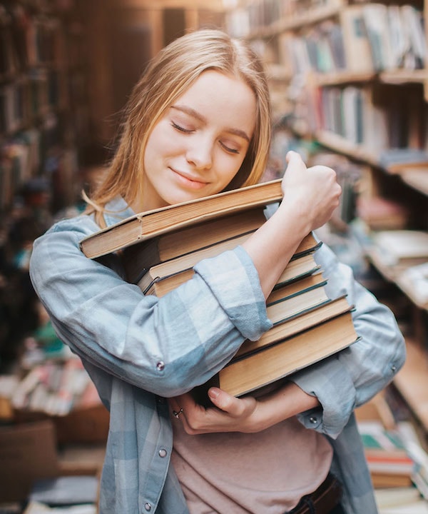 A young woman holding a collection of books