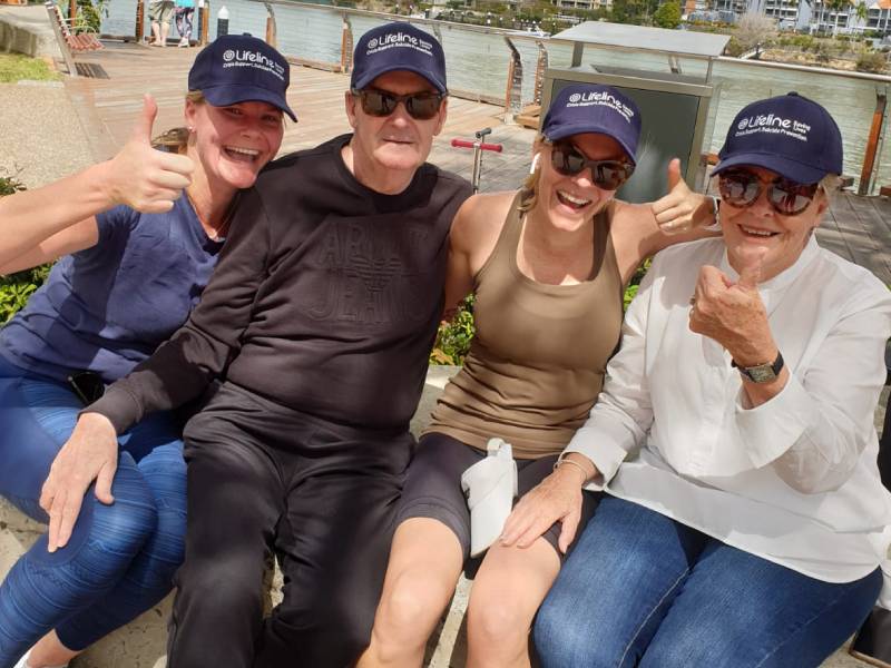 4 people with Lifeline hats smiling and giving thumbs up on a bench