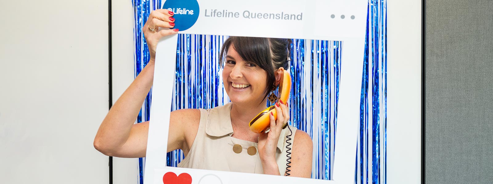 A woman holding up a social media cut-out
