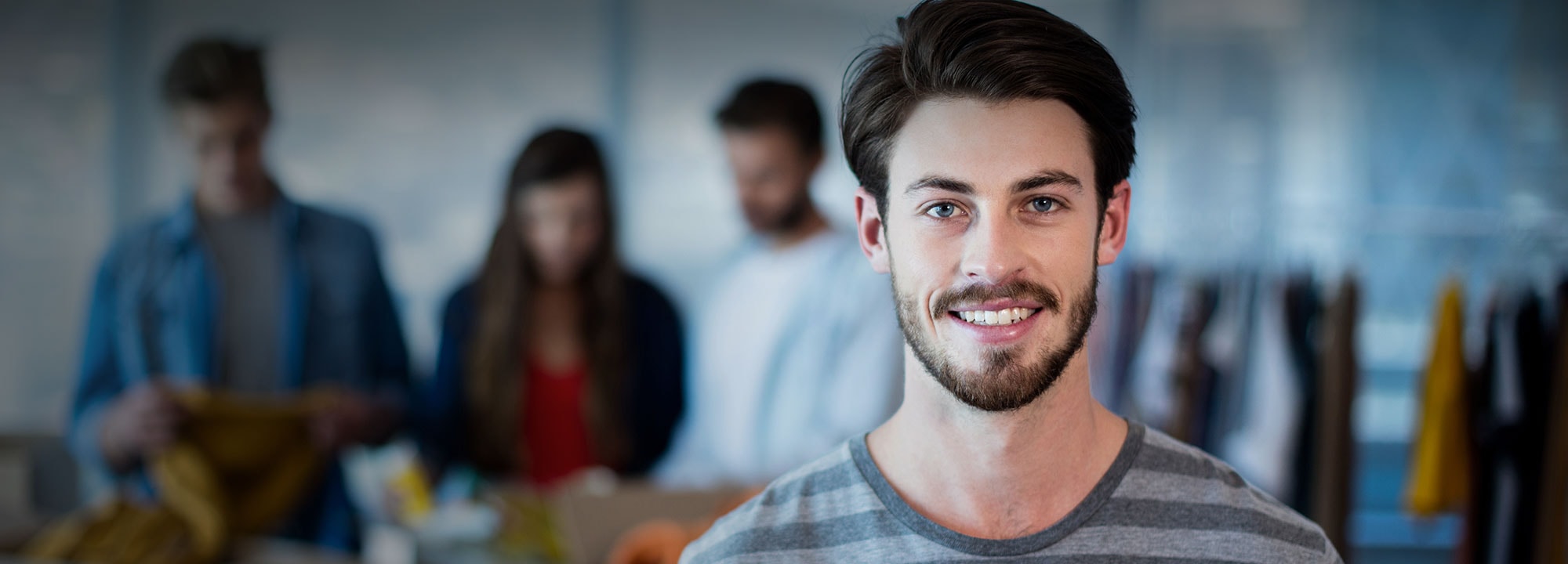 A man smiling with workers in the background