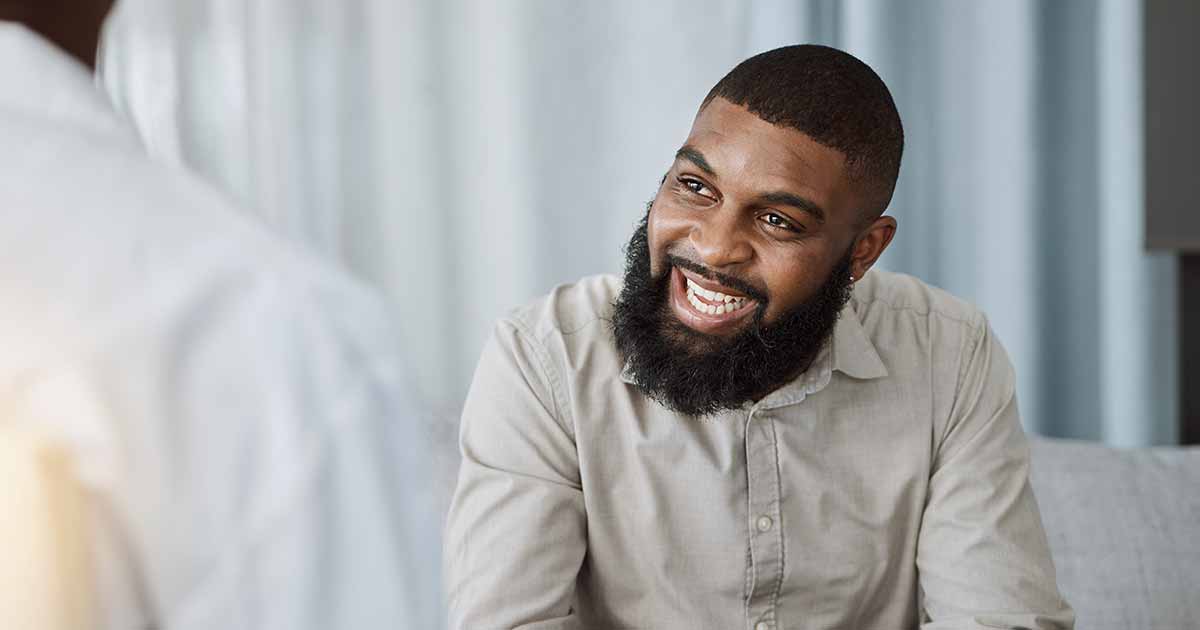 A happy man smiling at an unknown person in the foreground