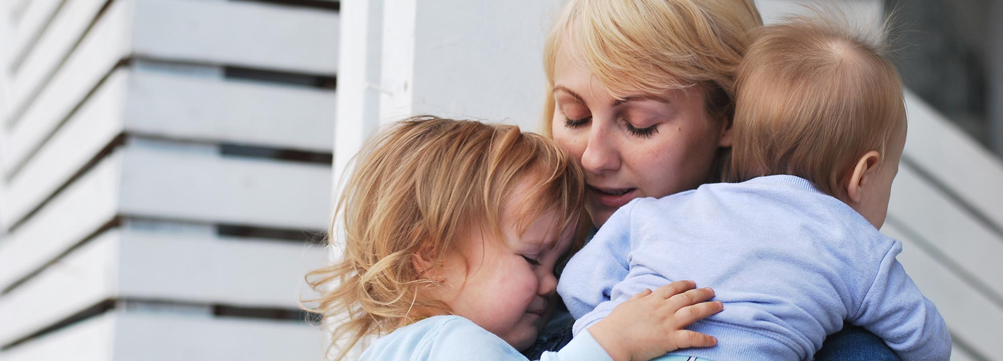 A mum holds her two young children close.