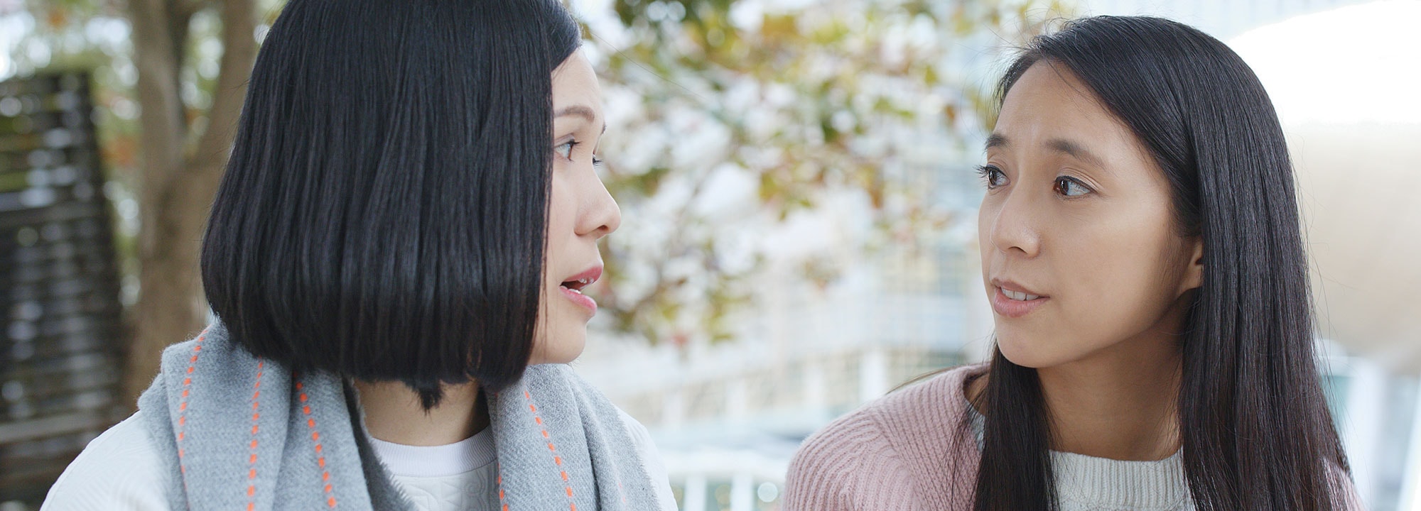 Two young women have a conversation in a park.